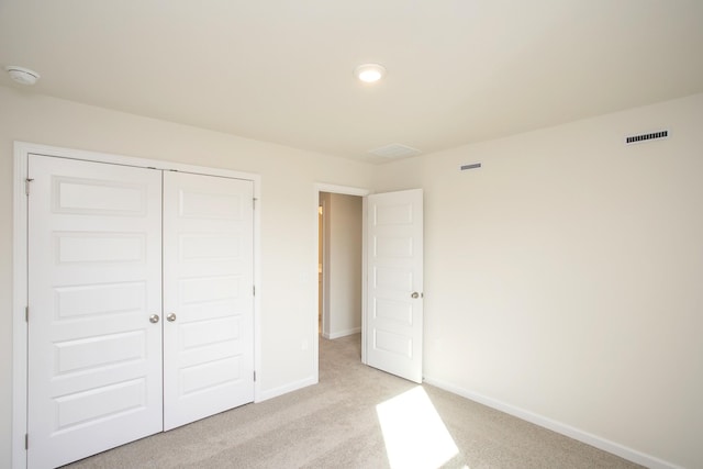 unfurnished bedroom featuring light colored carpet and a closet