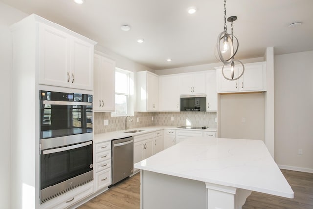 kitchen with white cabinetry, stainless steel appliances, a center island, and sink