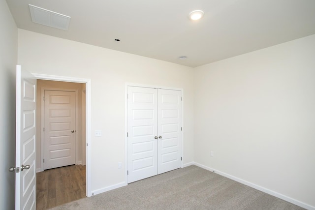 unfurnished bedroom with light carpet and a closet