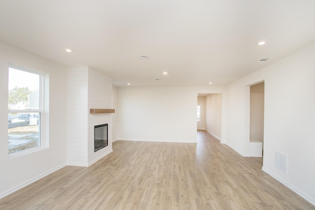 unfurnished living room featuring a large fireplace and light wood-type flooring