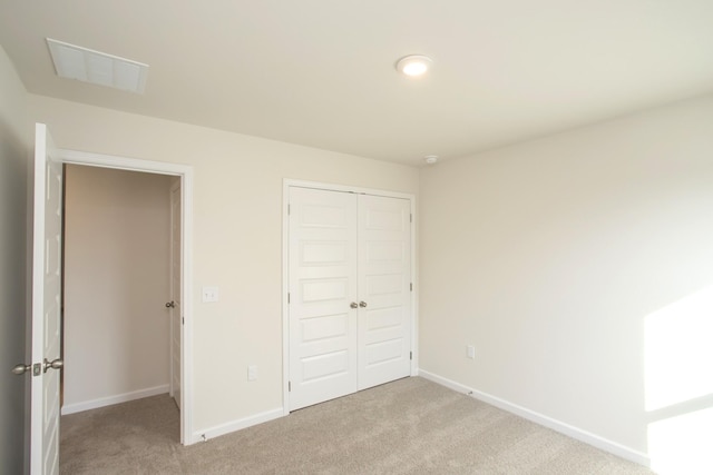 unfurnished bedroom with light colored carpet and a closet