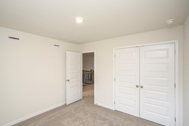 unfurnished bedroom with light carpet and a closet