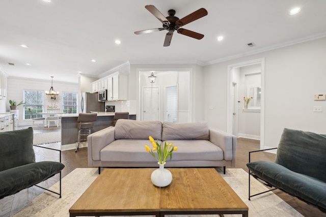 living room featuring crown molding, ceiling fan with notable chandelier, and light hardwood / wood-style floors