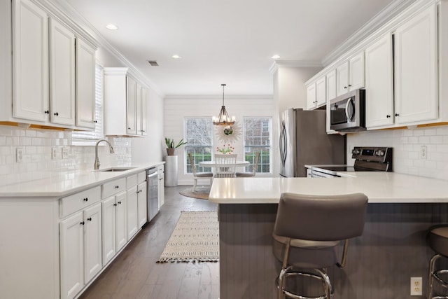 kitchen with white cabinetry, stainless steel appliances, a breakfast bar, and sink