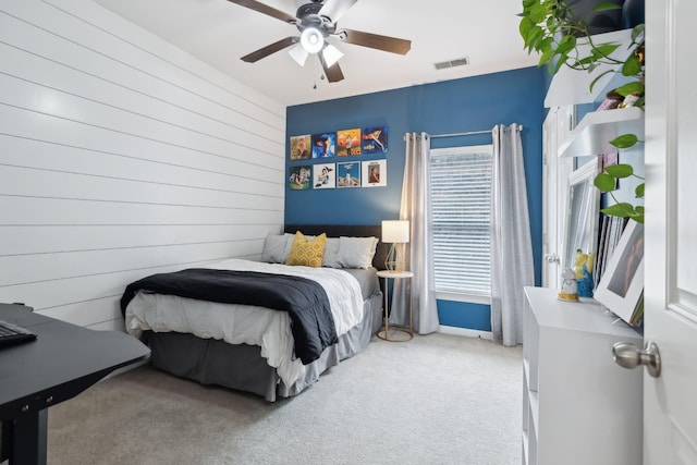 bedroom with ceiling fan, wooden walls, and carpet