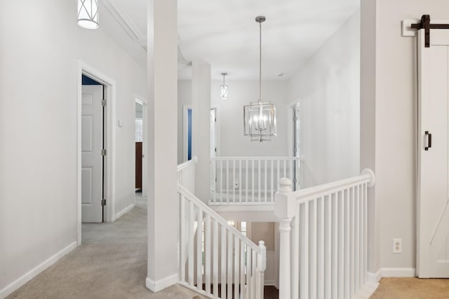 hallway featuring a barn door, light carpet, and a chandelier