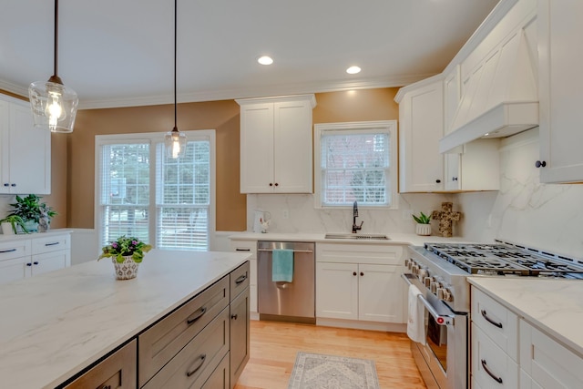 kitchen featuring sink, white cabinets, hanging light fixtures, stainless steel appliances, and custom range hood