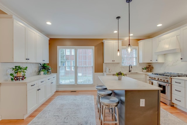 kitchen with pendant lighting, a breakfast bar, high end stainless steel range oven, white cabinetry, and a center island