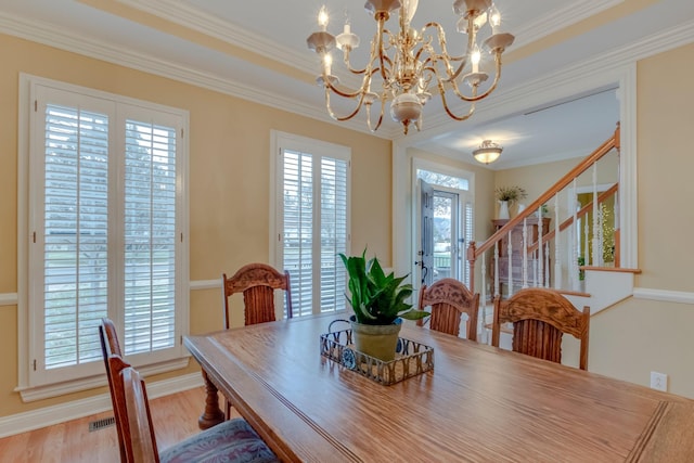 dining space featuring a notable chandelier, wood-type flooring, ornamental molding, and a healthy amount of sunlight