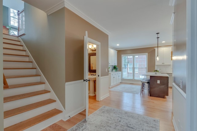 interior space featuring a kitchen island, decorative light fixtures, white cabinetry, a breakfast bar area, and light hardwood / wood-style flooring