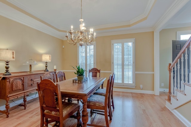 dining room featuring an inviting chandelier, a tray ceiling, ornamental molding, and light hardwood / wood-style floors