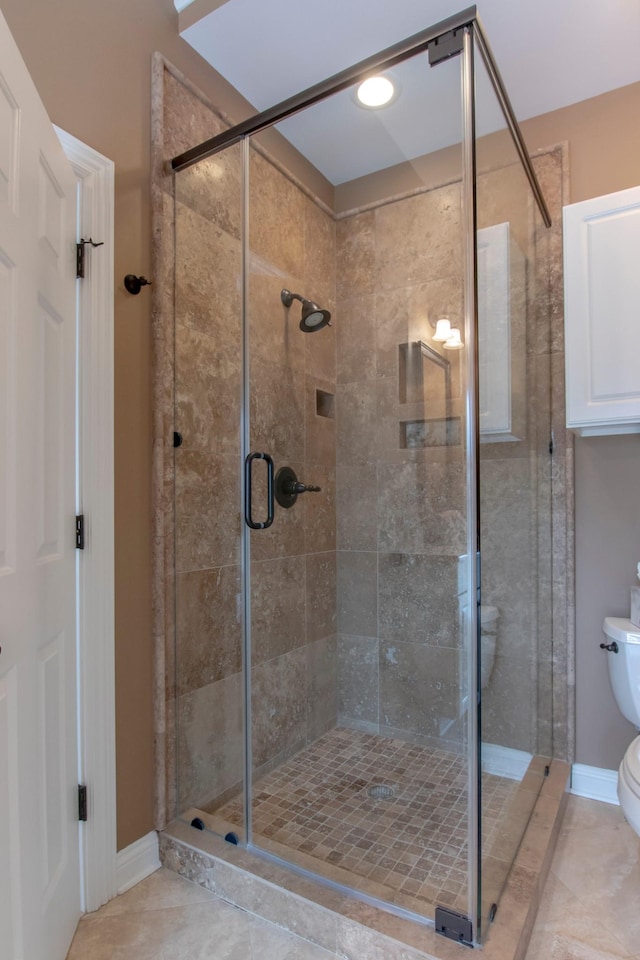 bathroom with a shower with shower door, tile patterned floors, and toilet