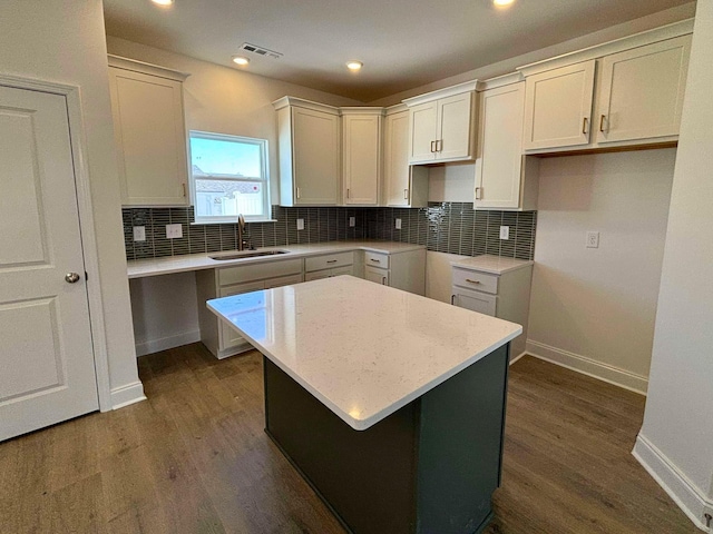 kitchen with decorative backsplash, sink, a kitchen island, and white cabinets