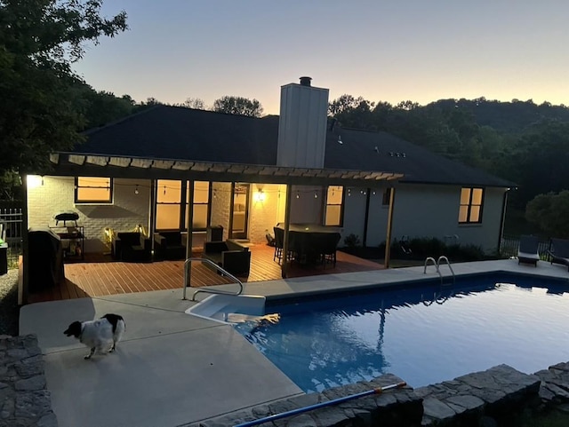 back house at dusk with a swimming pool side deck