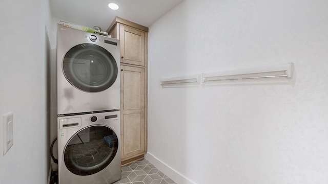 washroom featuring stacked washer and dryer, cabinets, and light tile patterned flooring