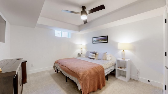 carpeted bedroom with a tray ceiling and ceiling fan