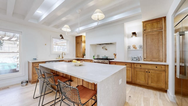 kitchen with a breakfast bar, a center island, range, beam ceiling, and light hardwood / wood-style flooring