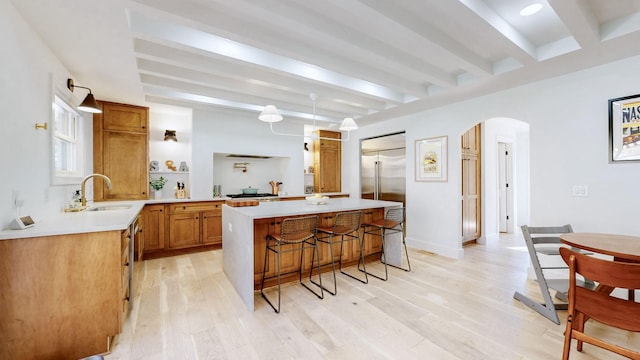 kitchen with a breakfast bar area, sink, a kitchen island, and light wood-type flooring