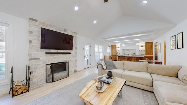 living room featuring lofted ceiling, a fireplace, and light hardwood / wood-style flooring