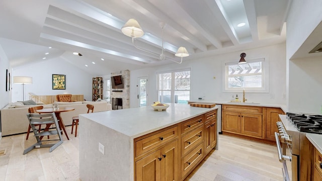 kitchen featuring gas stove, a center island, sink, and light wood-type flooring