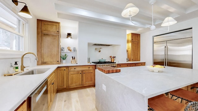 kitchen featuring sink, appliances with stainless steel finishes, beam ceiling, light hardwood / wood-style floors, and decorative light fixtures