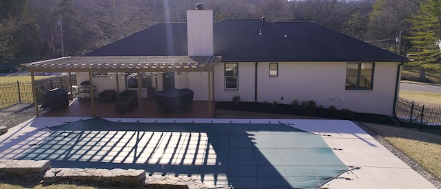 rear view of property with a patio area and a covered pool