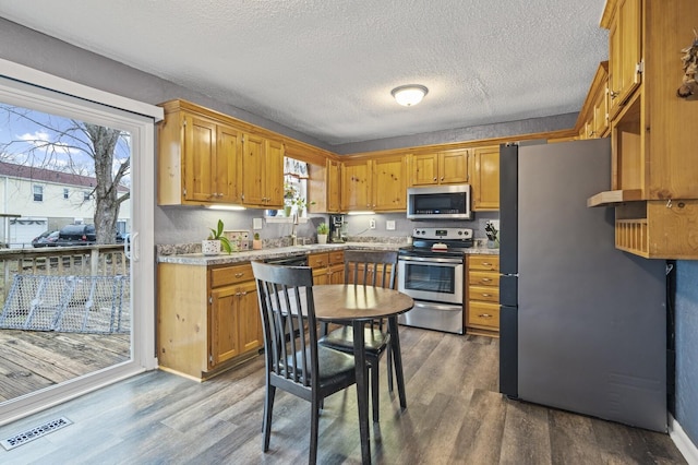 kitchen with wood-type flooring, appliances with stainless steel finishes, and a textured ceiling