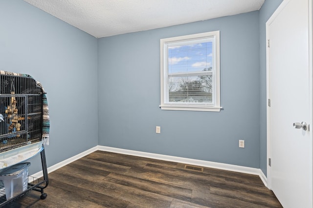 unfurnished room featuring dark wood-type flooring and a textured ceiling