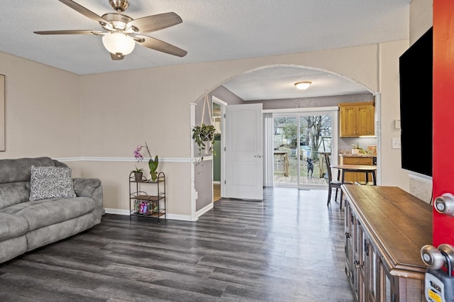 living room featuring ceiling fan, dark wood-type flooring, and a textured ceiling