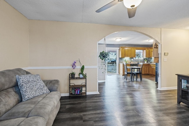 living room featuring ceiling fan, dark hardwood / wood-style floors, and a textured ceiling