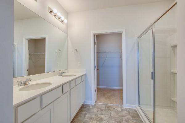 bathroom featuring a shower with door and vanity