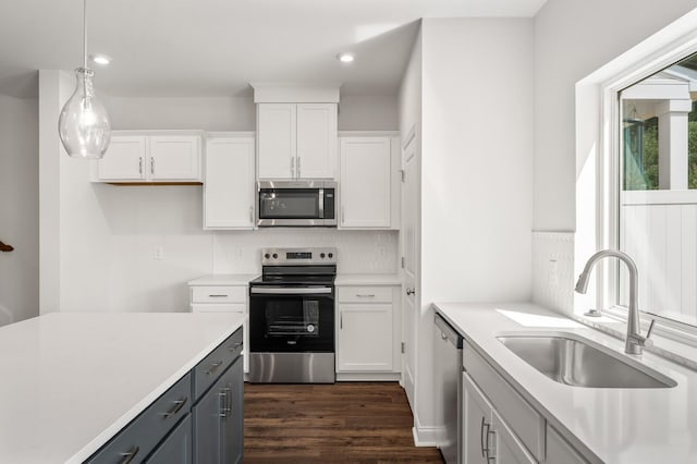 kitchen with white cabinetry, appliances with stainless steel finishes, decorative light fixtures, and sink