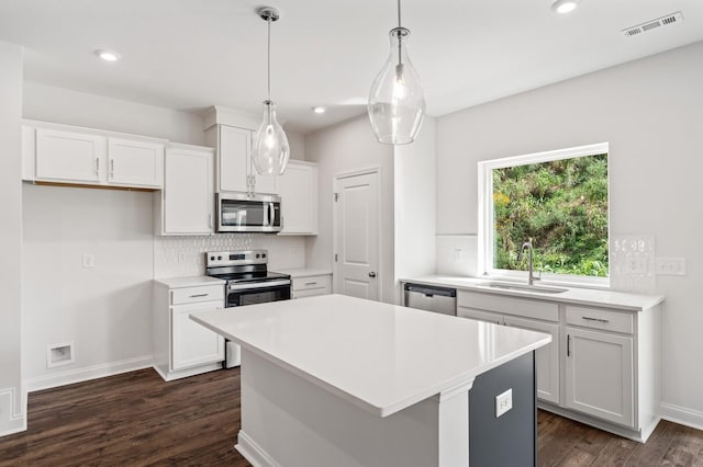 kitchen with sink, hanging light fixtures, white cabinets, and appliances with stainless steel finishes