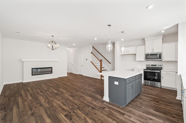 kitchen with stainless steel appliances, hanging light fixtures, a kitchen island, and white cabinets