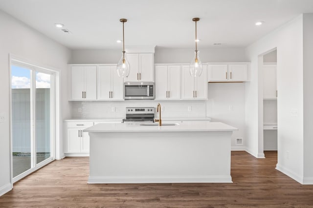 kitchen with sink, decorative light fixtures, an island with sink, stainless steel appliances, and white cabinets