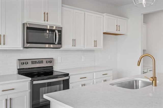 kitchen featuring sink, white cabinetry, backsplash, stainless steel appliances, and light stone counters