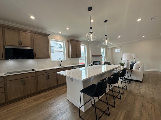 kitchen featuring visible vents, a kitchen island, a breakfast bar area, open floor plan, and black electric cooktop