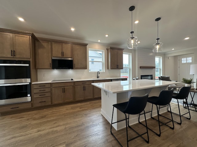 kitchen featuring a center island, pendant lighting, a breakfast bar area, stainless steel double oven, and a sink