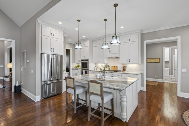 kitchen with pendant lighting, appliances with stainless steel finishes, an island with sink, and white cabinets