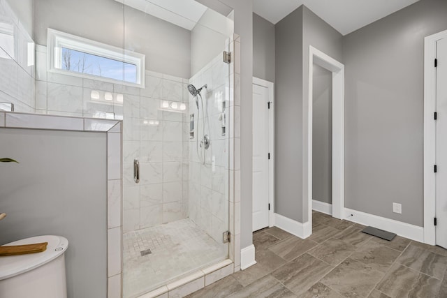 bathroom featuring a shower with shower door and toilet