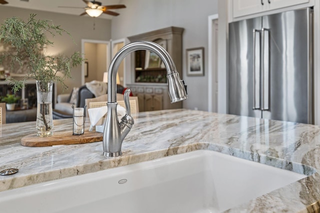 details with light stone counters, ceiling fan, high end fridge, and white cabinets