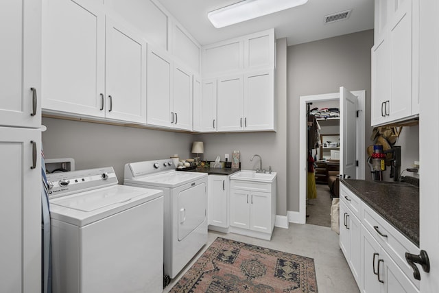 laundry area with sink, washing machine and dryer, and cabinets