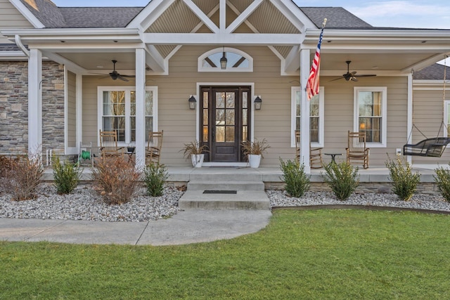 doorway to property with a porch, a yard, and ceiling fan