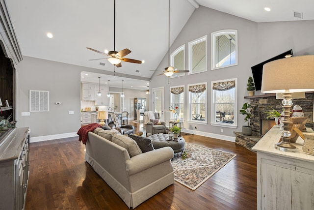 living room featuring a stone fireplace, high vaulted ceiling, and dark hardwood / wood-style floors