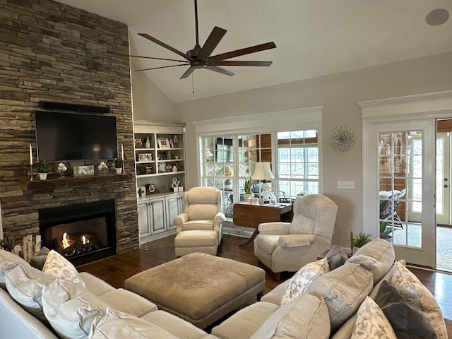 living room featuring a stone fireplace, dark wood-type flooring, high vaulted ceiling, and ceiling fan