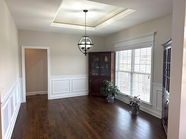 unfurnished dining area with dark hardwood / wood-style floors, a tray ceiling, and an inviting chandelier