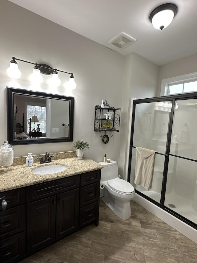 bathroom with vanity, a shower with door, and toilet