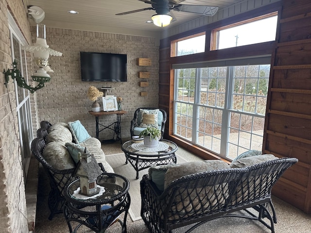 living room featuring brick wall, carpet floors, and ceiling fan