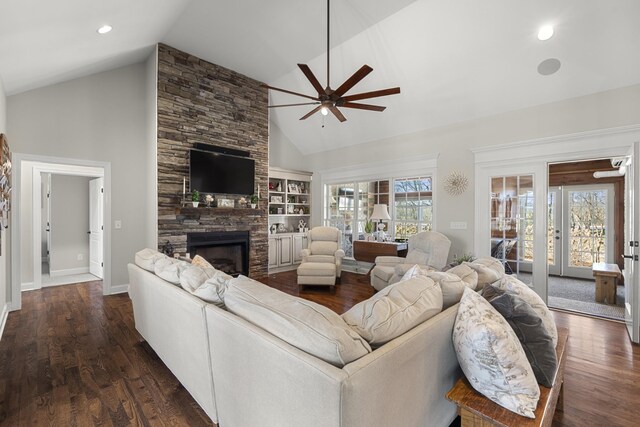 living area featuring high vaulted ceiling, dark wood-style flooring, a fireplace, a ceiling fan, and baseboards