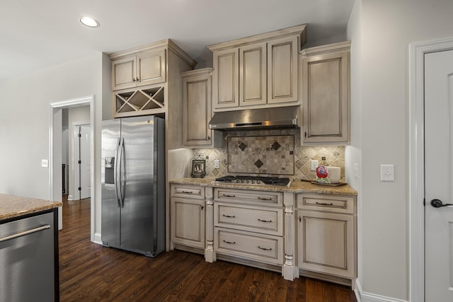 kitchen with stainless steel appliances, cream cabinetry, decorative backsplash, and under cabinet range hood